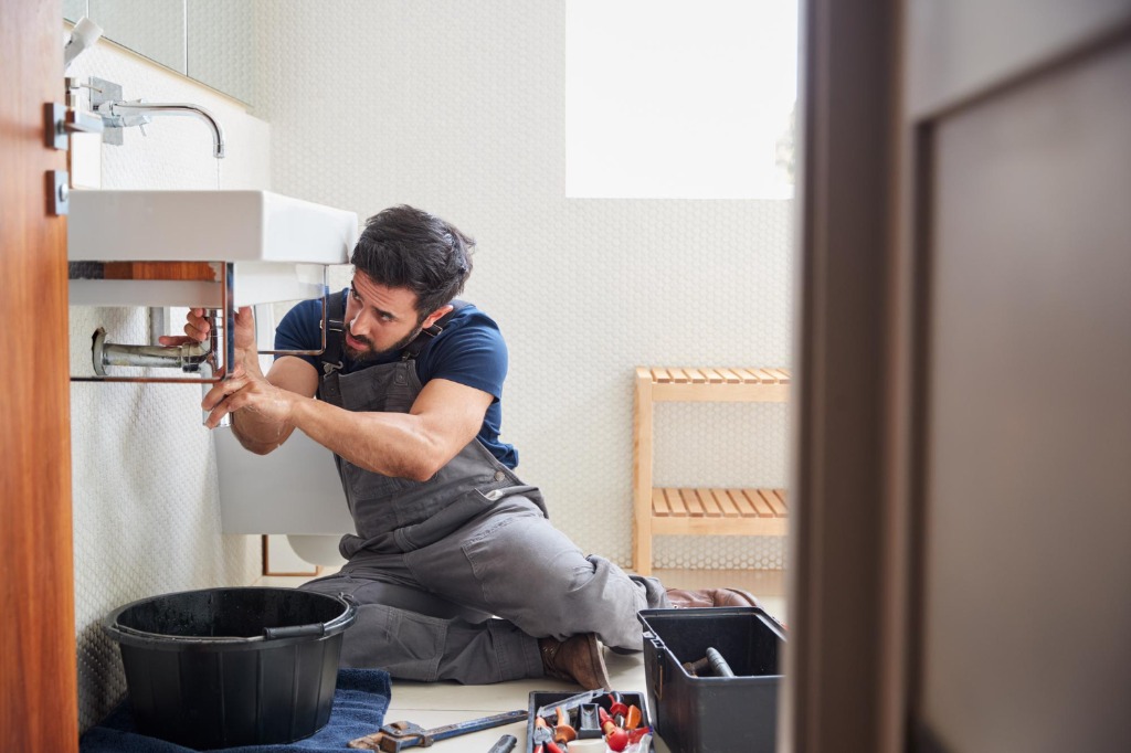 Emergency plumber in Dubai diagnosing and repairing leaking wash basin pipes